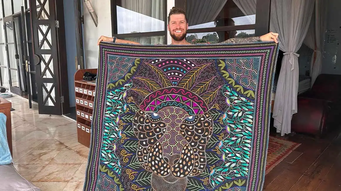 Homme tenant une tapisserie avec une envergure de bras complète d'une impression de style mandala d'un jaguar