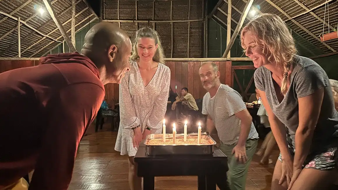 Quatre personnes se tenaient autour d'un gâteau d'anniversaire avec quatre bougies allumées.