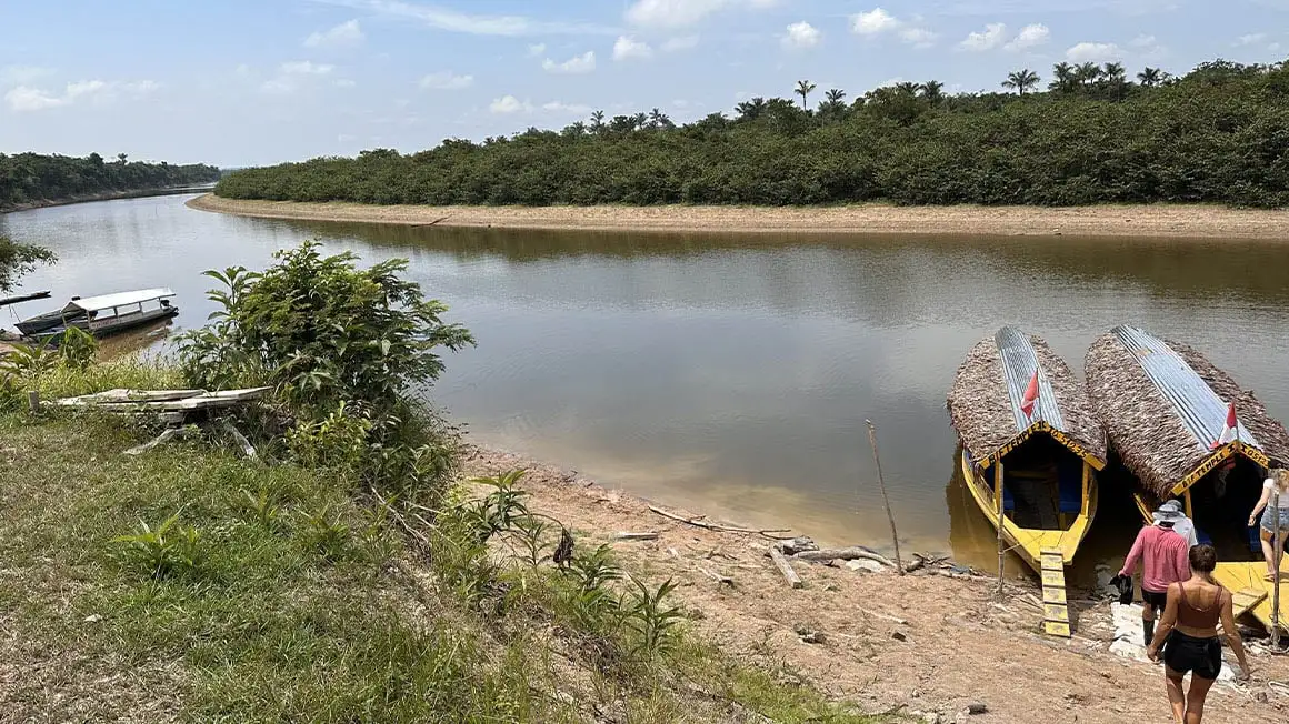 Les voyageurs se dirigeant vers l'Amazonie embarquent en canoë sur la plage de la rivière Iquitos.
