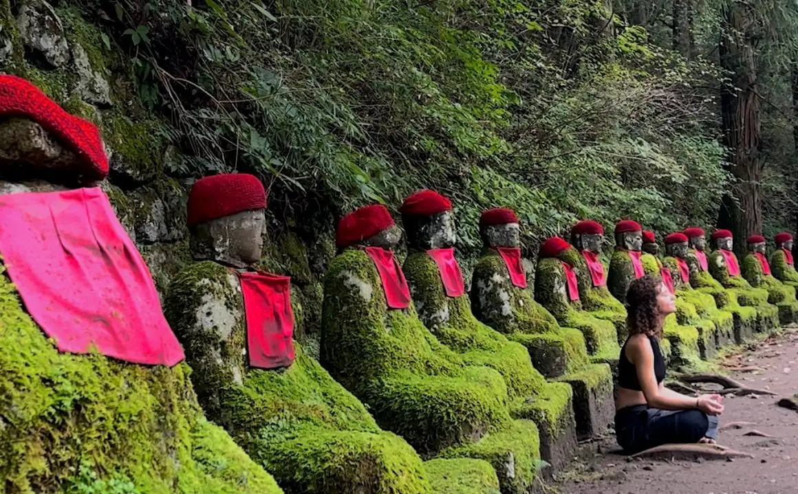 日光の寺院で仏像に囲まれて瞑想する少女。