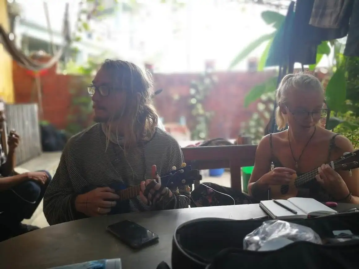 Laura e Ziggy tocando cavaquinho no jardim de uma pousada