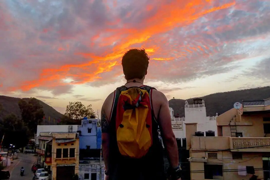 homme regardant un coucher de soleil épique à Bundi lors d'une randonnée en Inde