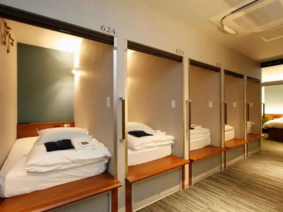 Kamar pod besar dengan tirai dan pencahayaan disusun berjajar di Gardens Cabin