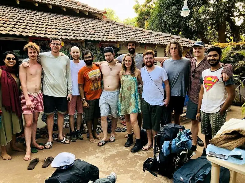 deux personnes et un chien marchant vers l'océan pendant un coucher de soleil jaune orange tout en restant à Goa