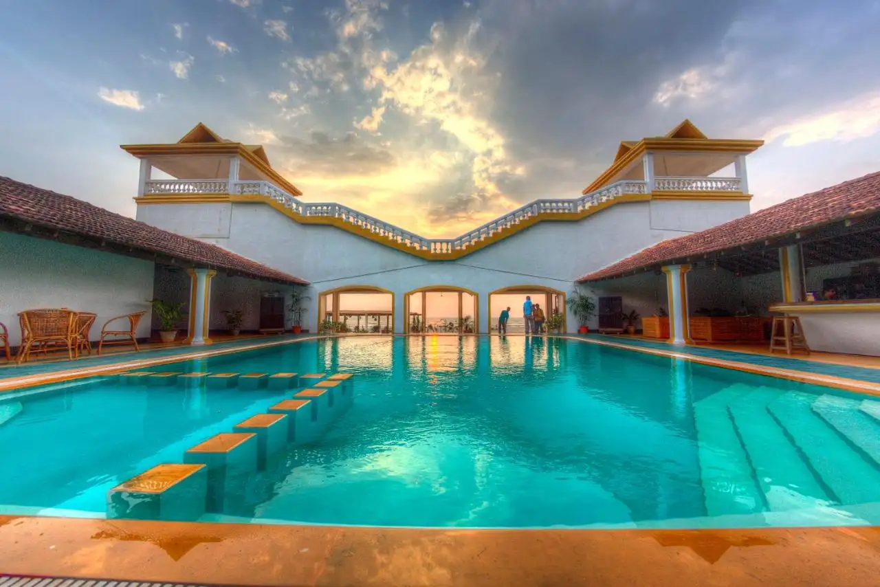 superbe piscine creusée avec eau turquoise surplombant un élégant pont de style villa européenne blanc et orange et l'océan
