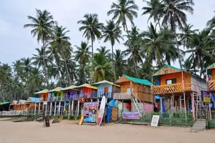 deux personnes faisant du yoga sur un rocher au bord de l'océan lors d'un incroyable coucher de soleil orange à Goa en Inde