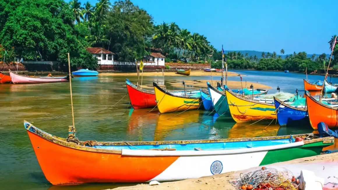 bateaux colorés dans la mer à Goa avec des maisons de bord de mer traditionnelles derrière eux