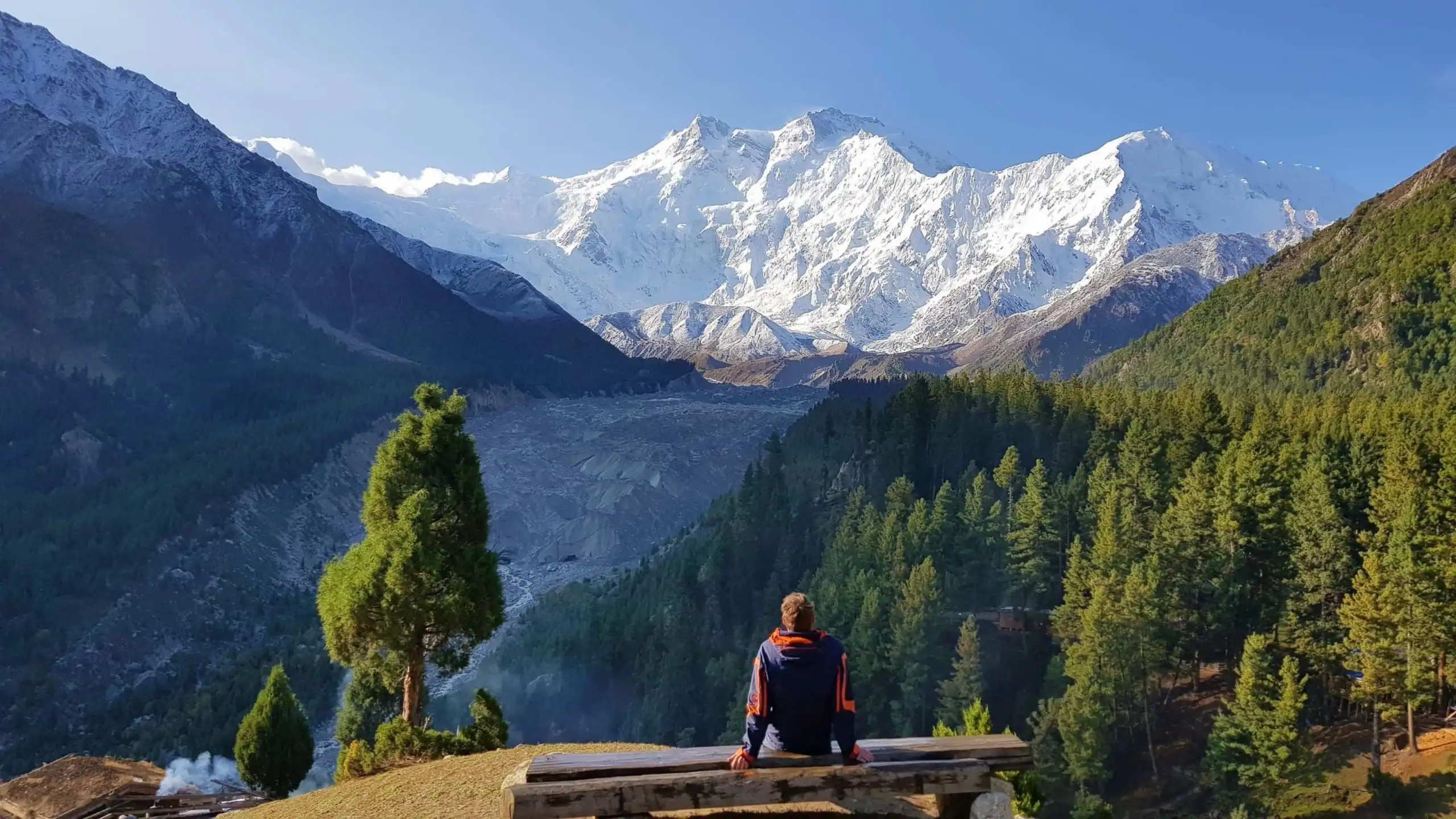 homem sentado olhando para a vista da montanha, nanga parbat em Fairy Meadows Paquistão