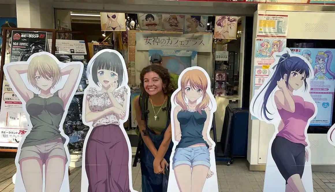 Seorang gadis berdiri di antara potongan karton karakter anime di Kyoto, Jepang.