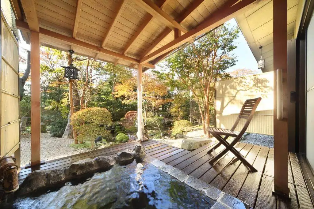 木の低いテーブルと黒い椅子が4脚ある広々とした箱根旅館。