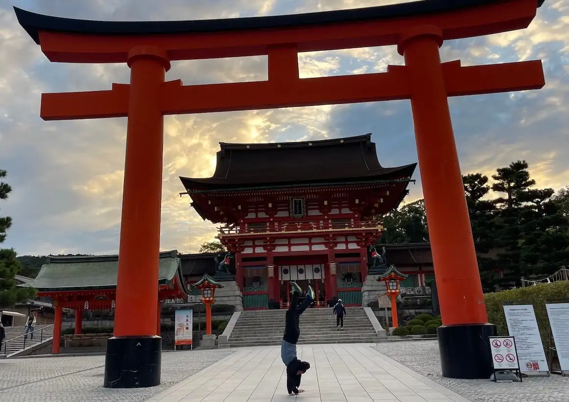 Cara faz parada de mãos sob santuário em Kyoto, Japão.