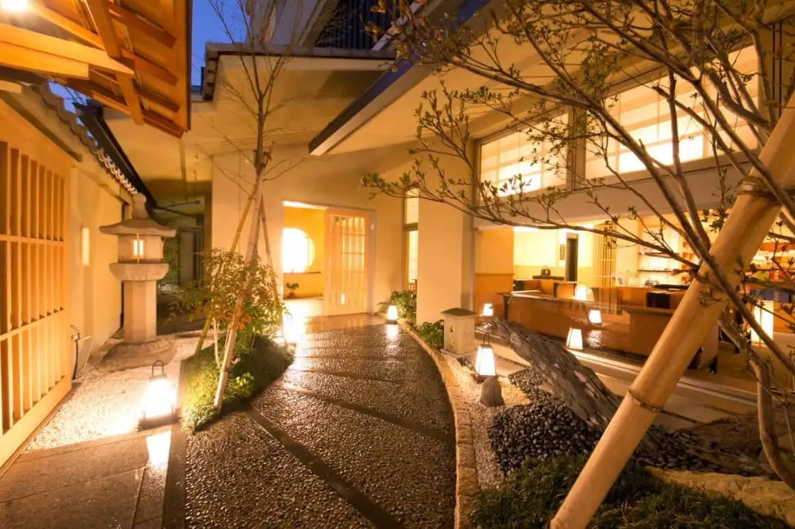 伝統的な旅館(石部小路夢庵)の客室で、布団 2 台と小さなテーブルと椅子が備わっています。
