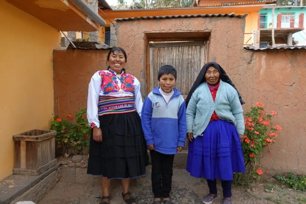 trois membres d'une famille péruvienne souriant pour une photo chez eux