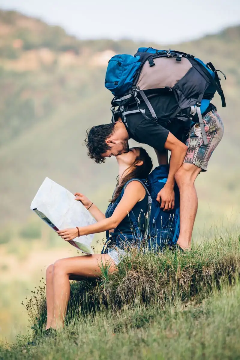 casal mochileiro se beijando enquanto uma garota segura um mapa enquanto viaja
