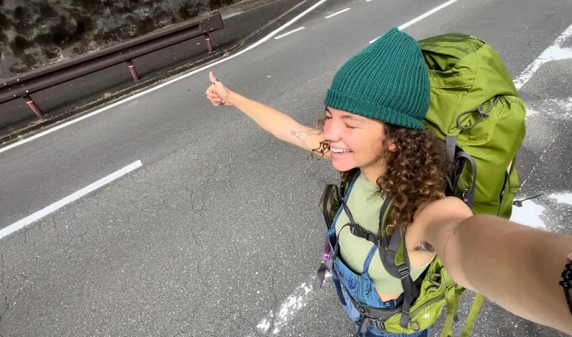 Une auto-stoppeuse solo prend un selfie en attendant un trajet au Japon.