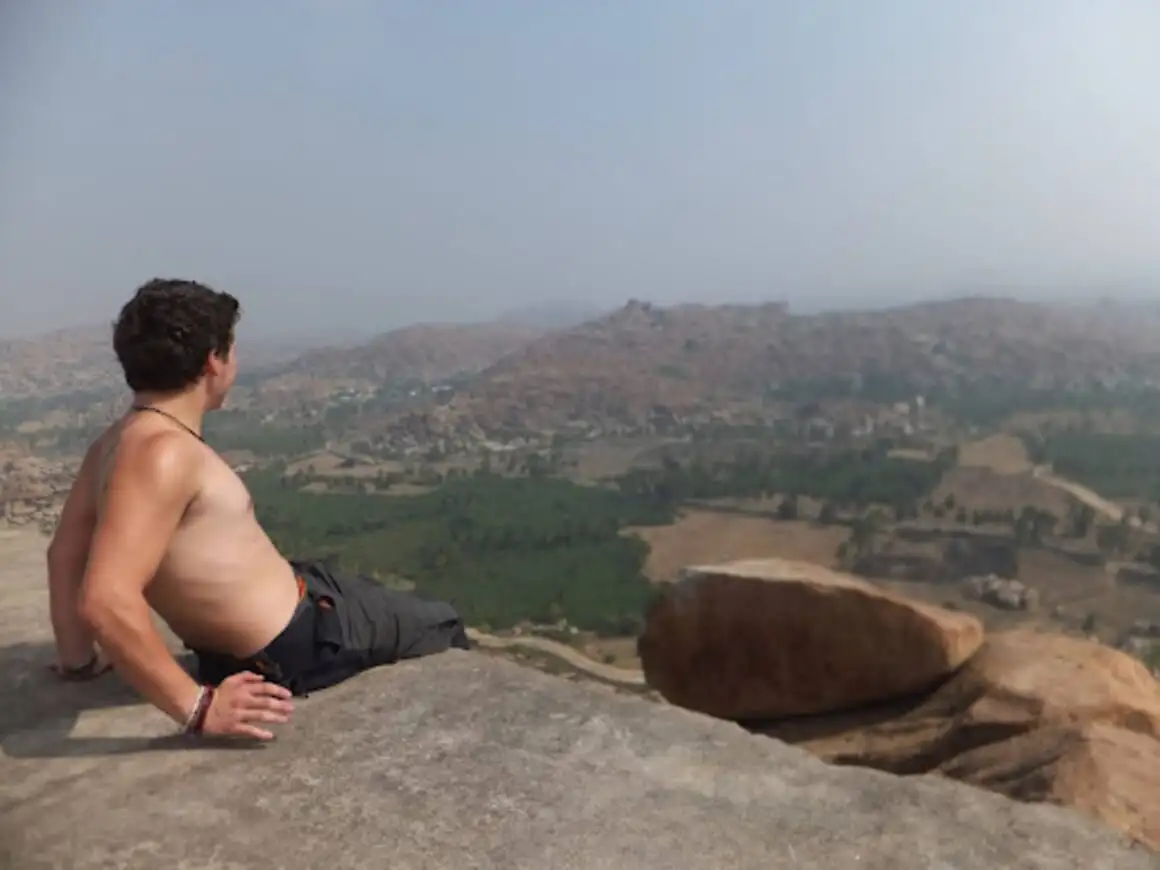 Sem camisa estará sentado no topo de um penhasco apreciando uma vista deslumbrante da Índia.
