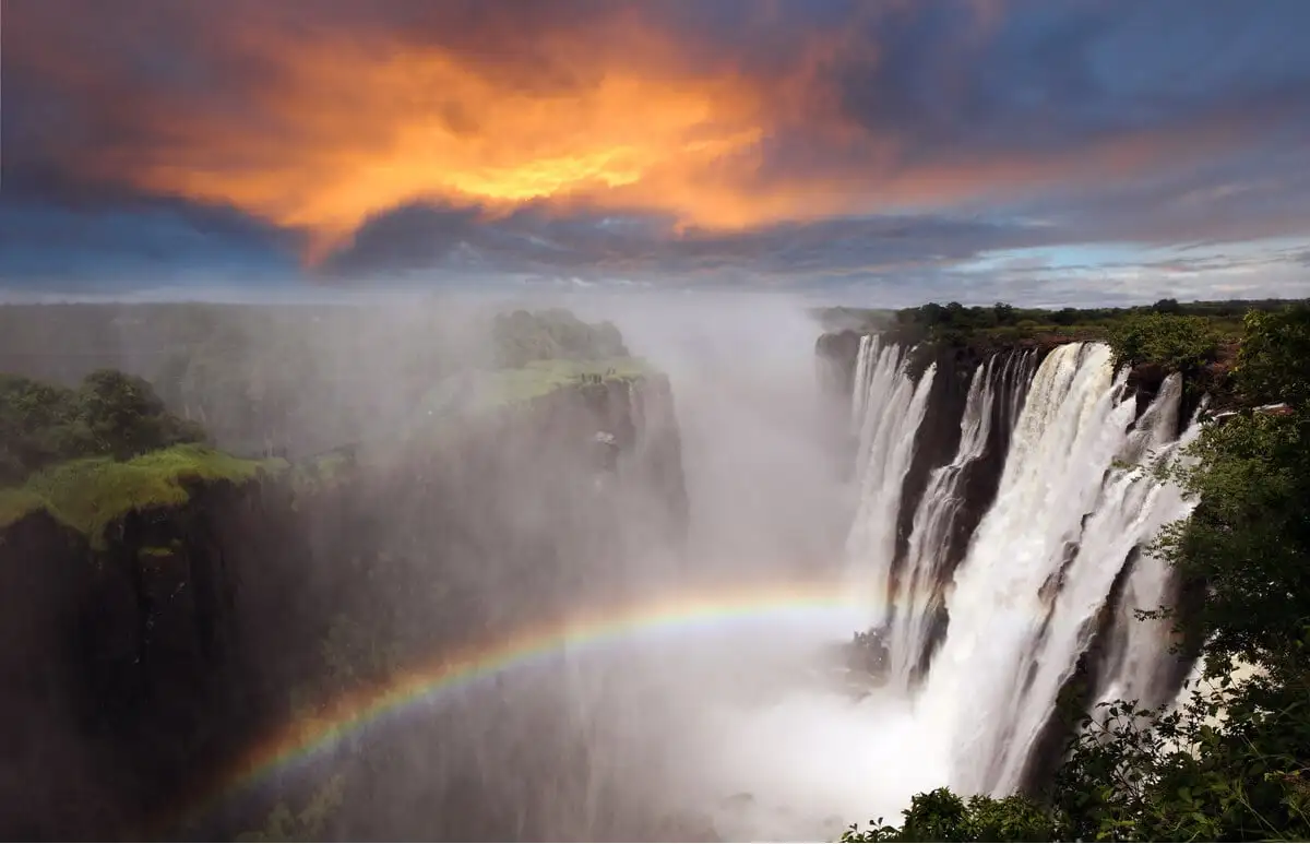 l'une des cascades les plus étonnantes du monde avec un arc-en-ciel et un coucher de soleil orange