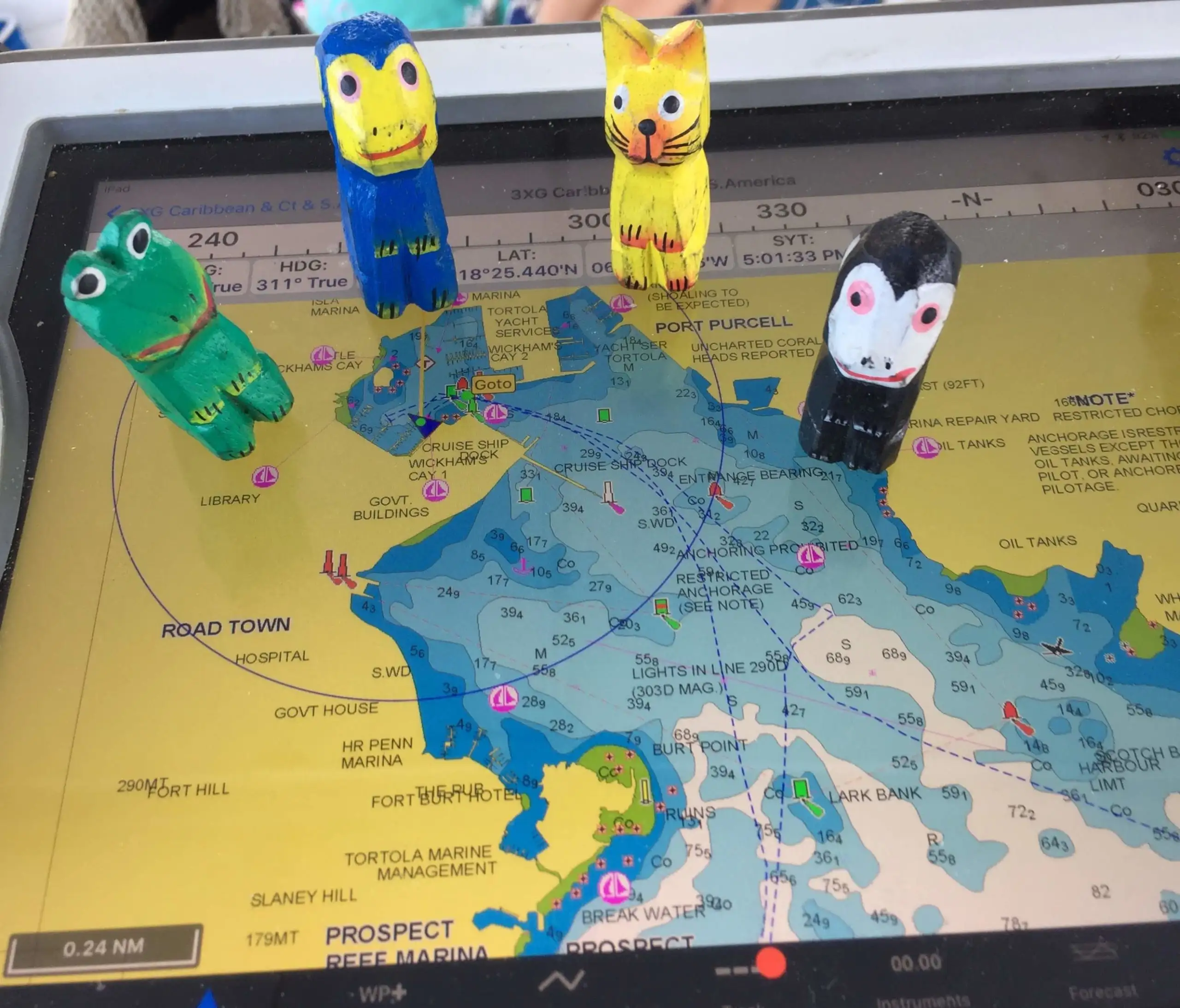 Quatro pequenas estatuetas estão em um chartplotter eletrônico enquanto aprendem a navegar em um veleiro.