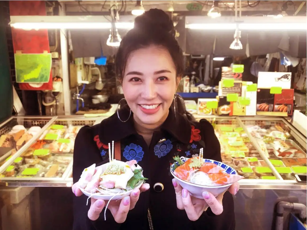 Uma mulher segura dois pratos de comida de rua no Japão.