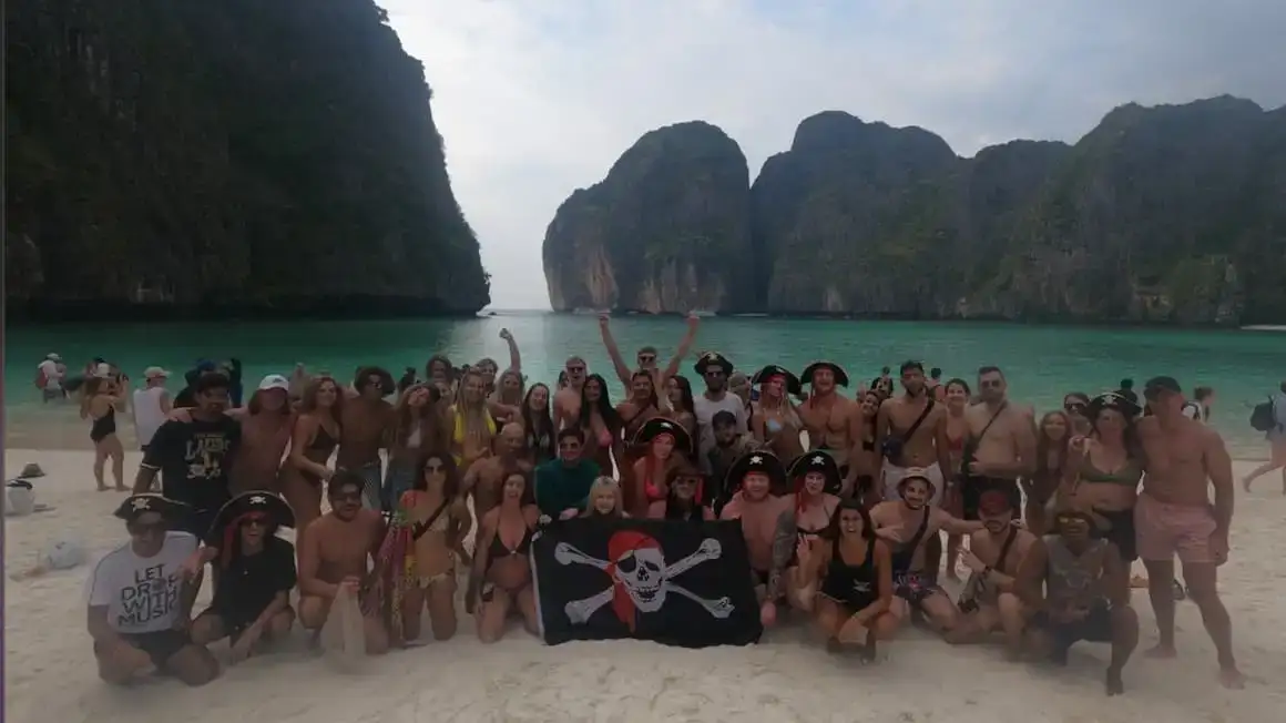 un grand groupe de personnes à la plage de Maya en Thaïlande, se réunissant pour une photo de groupe agissant comme des pirates