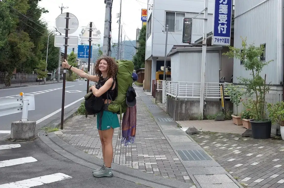Une fille souriante et faisant du stop à travers le Japon.