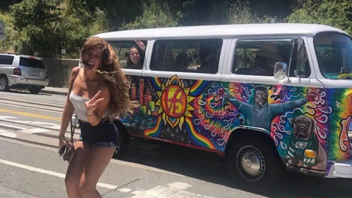 Une fille souriante devant une camionnette hippie en Californie