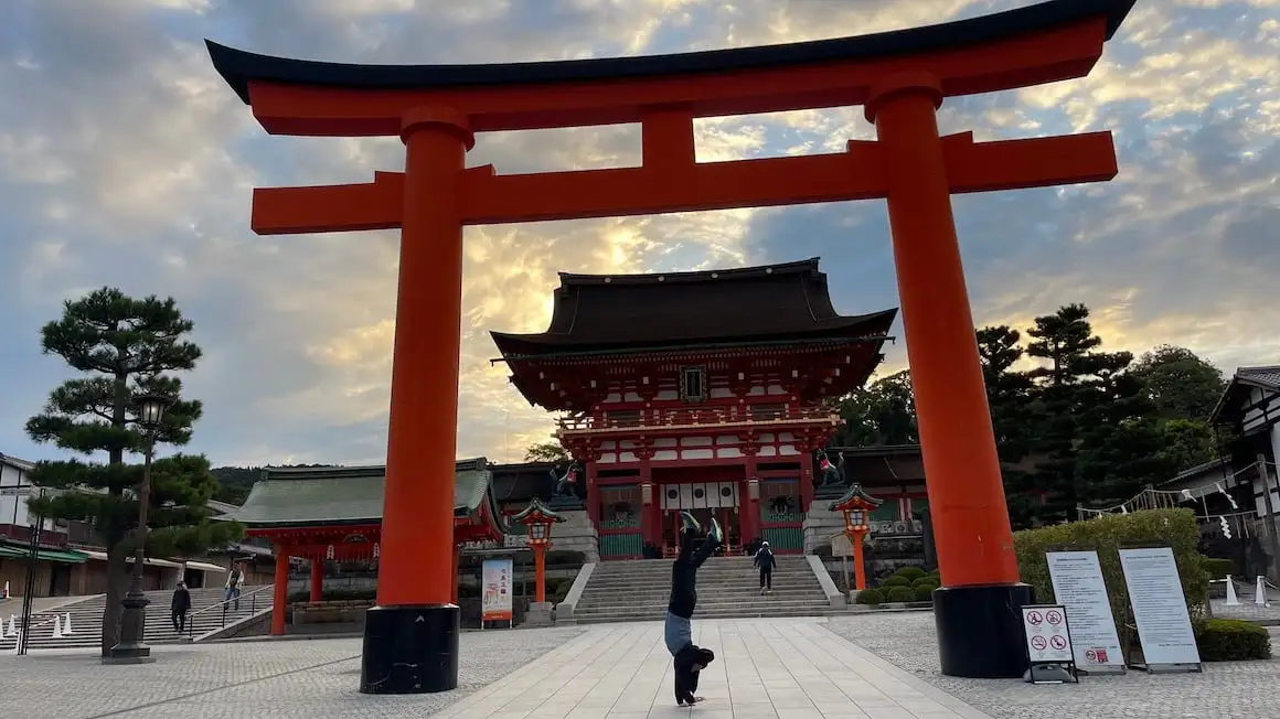 Een man doet een handstand bij de ingang van de tempel in Kyoto, Japan.