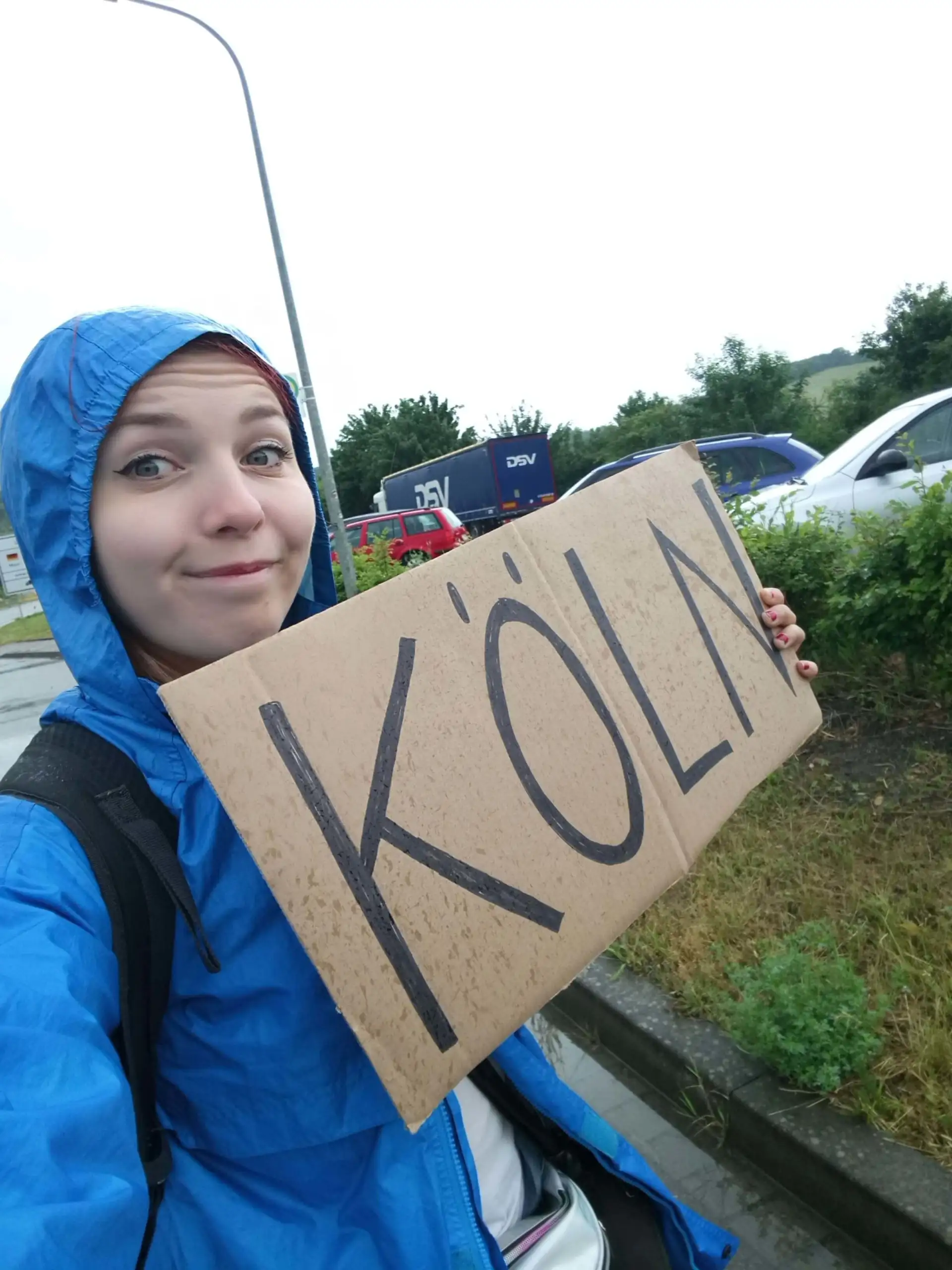 garota pedindo carona com uma capa de chuva azul