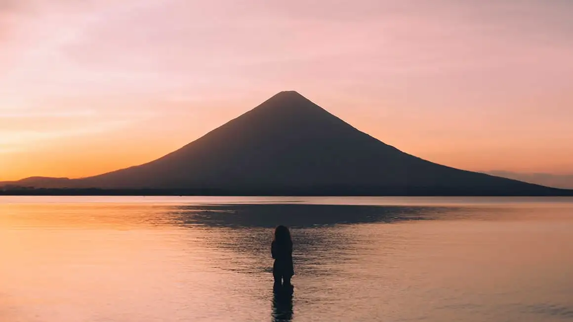 fille dans le lac regardant le coucher du soleil