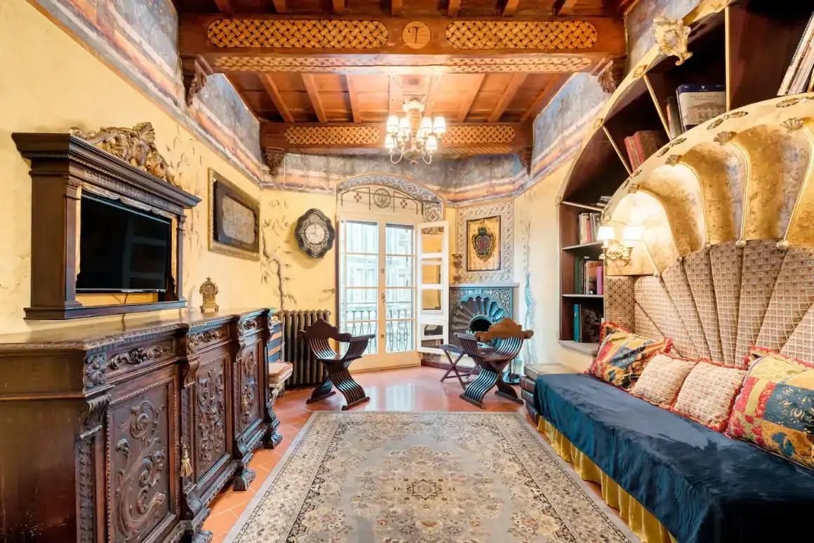 Priestranná spálňa v Airbnb s TV, posteľou, stolom a stoličkami. Môžete vidieť schodisko oproti stene, ktoré vedie na druhé poschodie.
