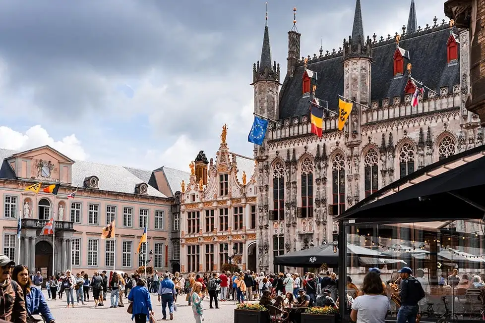 Edifícios ornamentados e uma igreja numa praça em Bruges, Bélgica