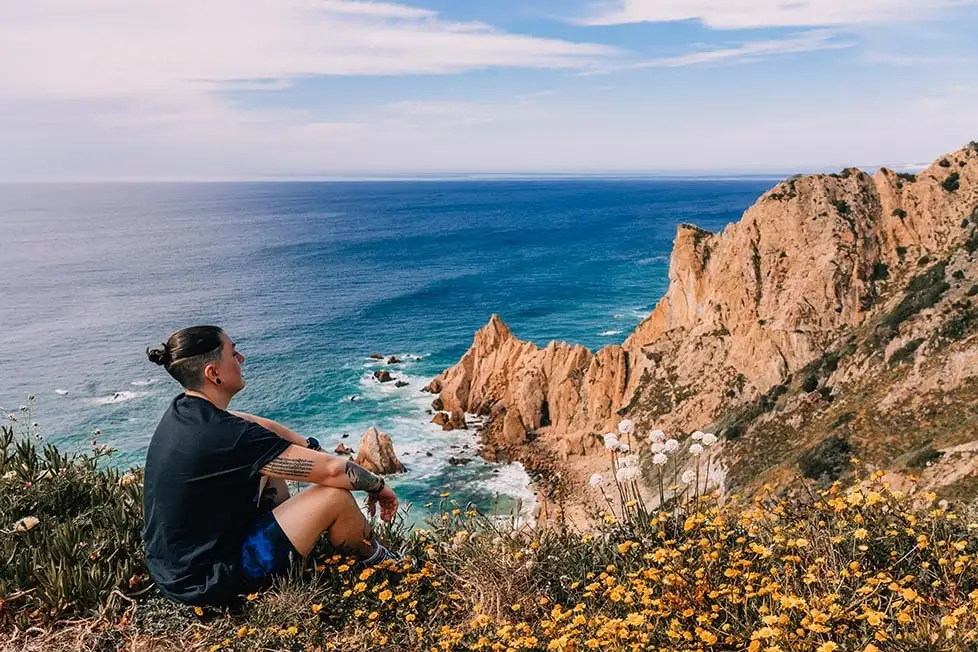 Uma pessoa olha para as falésias rochosas de Portugal