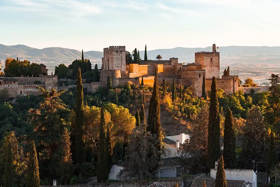 Le soleil frappe l'Alhambra au coucher du soleil avec les montagnes derrière