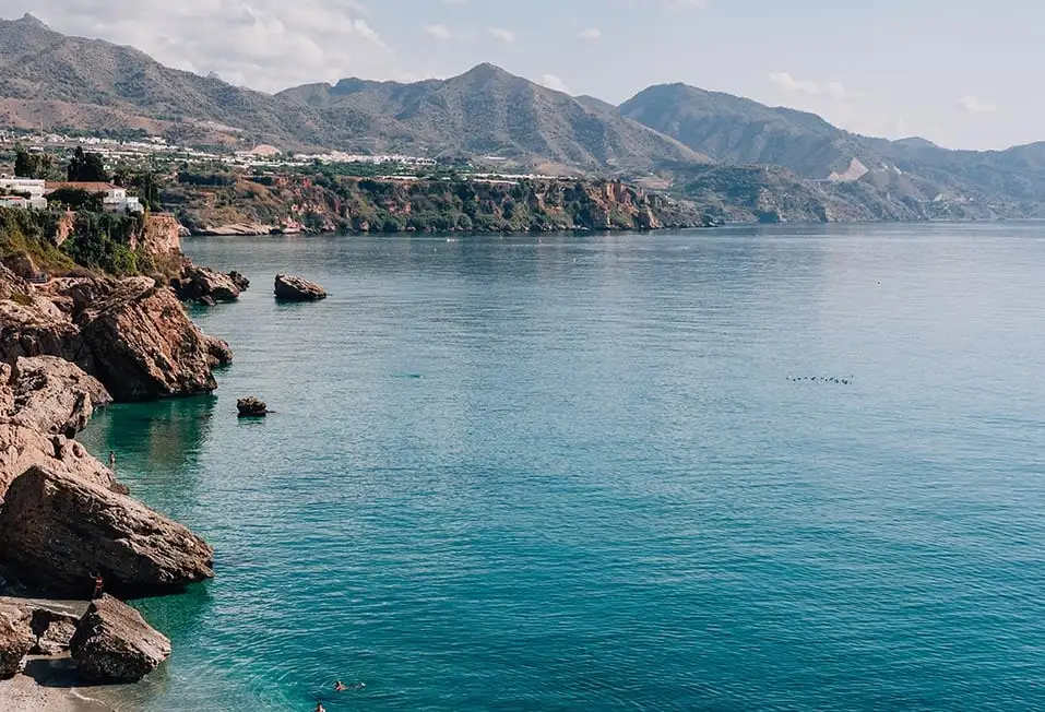 Une plage rocheuse et un littoral avec des montagnes en arrière-plan