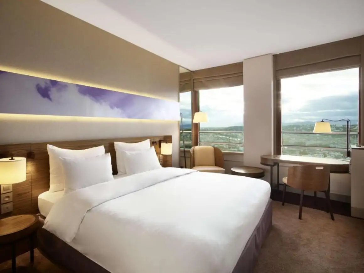 ห้องนอนเรียบง่ายทันสมัยที่ Radisson Blu Hotel Lyon หน้าต่างบานใหญ่ในห้องมองเห็นวิวภูเขา