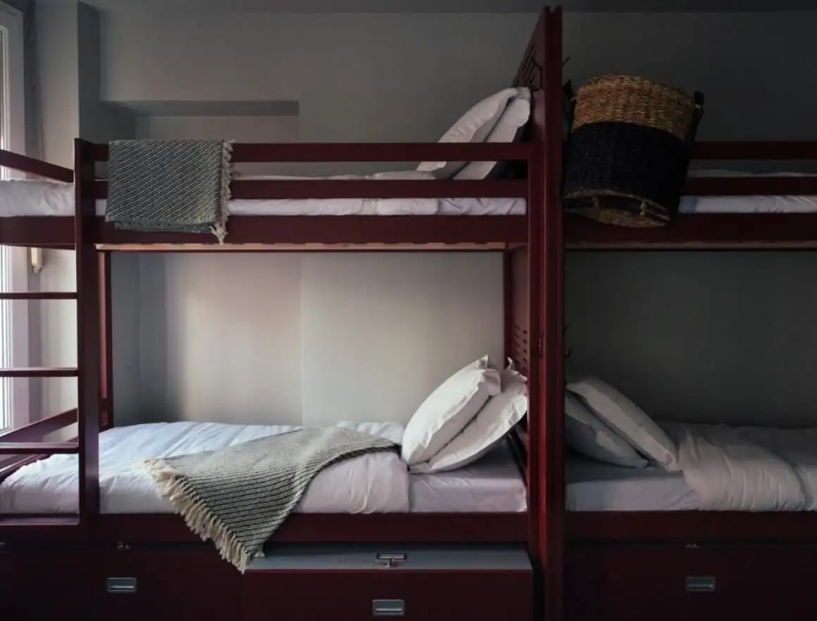 ห้องพักรวม Ho36 Hostel แสดงให้เห็นเตียงไม้สองชั้นพร้อมชุดผ้าปูเตียงสีขาวและผ้าห่มเสริม