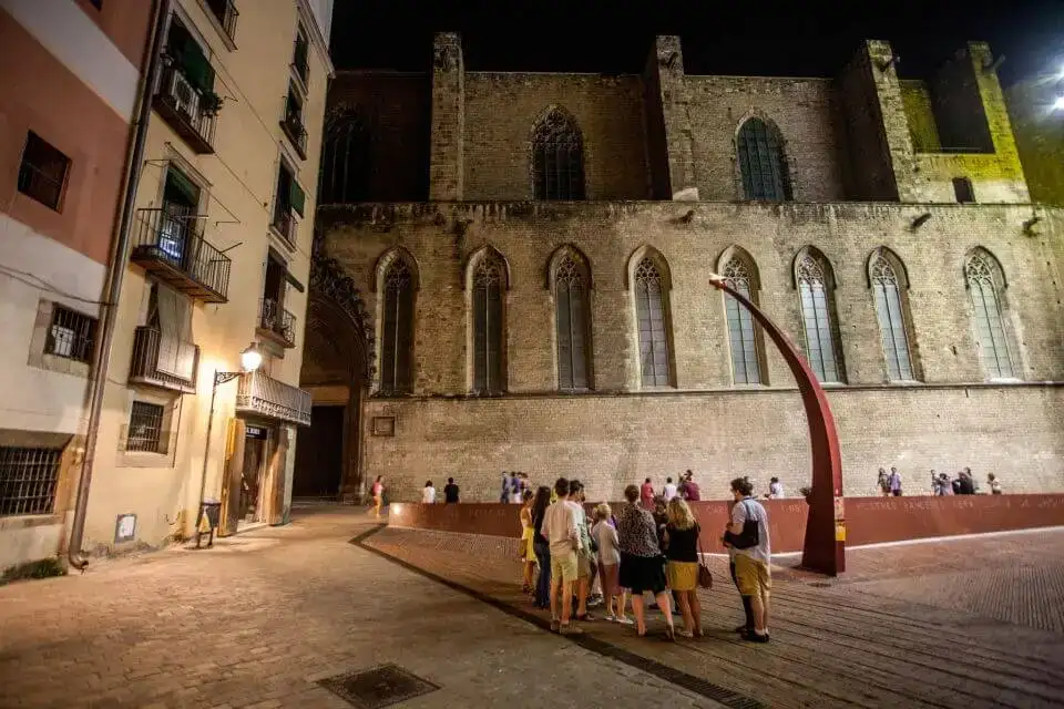 Un groupe de touristes debout devant le Fossar de les Moreres à Barcelone la nuit