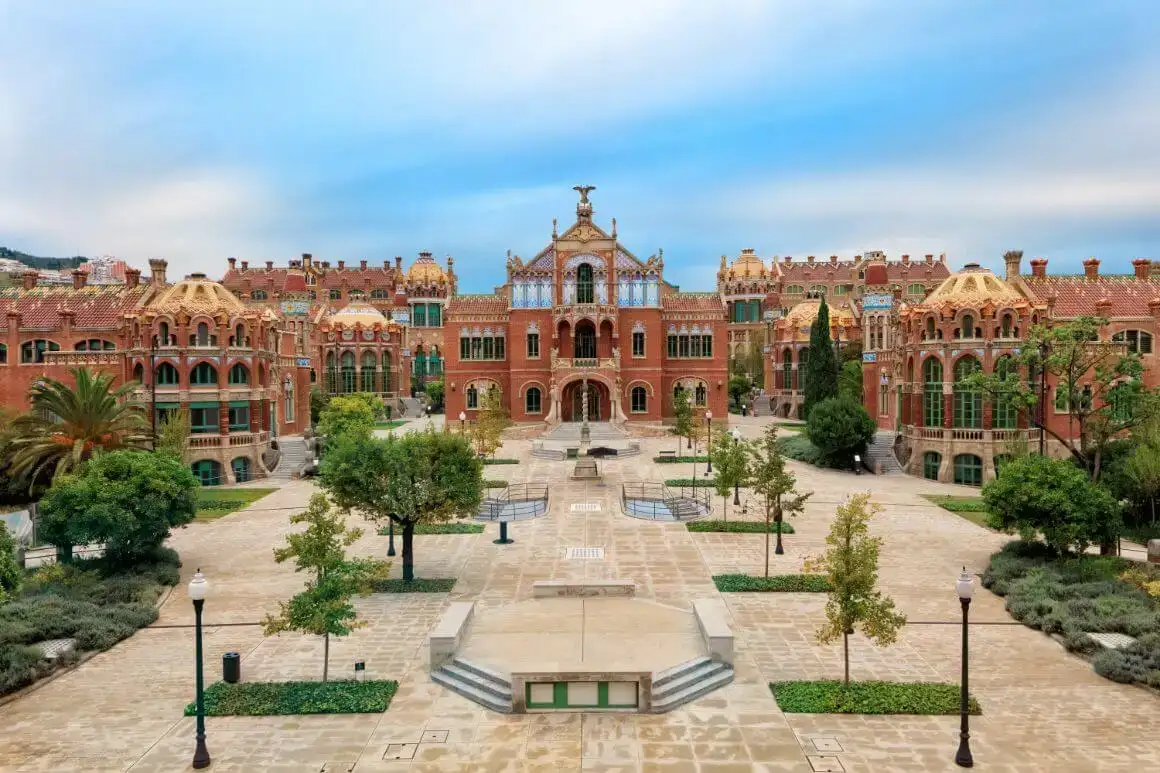 Bâtiments en brique et en pierre et grande cour ornée d'arbres et d'une fontaine à l'hôpital de Santa Creu i Sant Pau, Barcelone