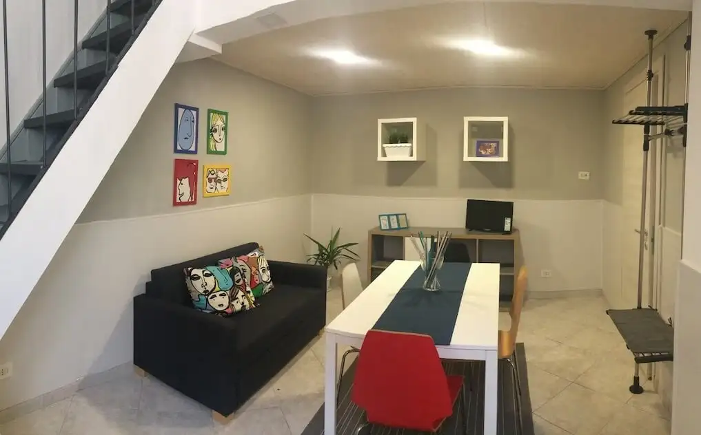 Skats uz iekšpagalmu no The Yard Hostel ar daudziem logiem, mīkstu apgaismojumu un kokiem Katānijā, Sicīlijā.