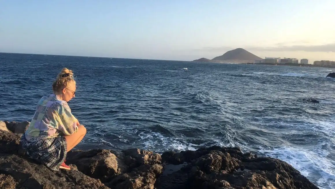 Fille assise sur les rochers près de l'océan