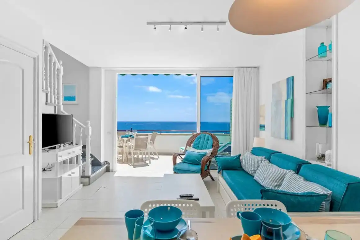 Espace de vie blanc et bleu du Penthouse The First Line Sea View avec vue sur le balcon et l'océan.