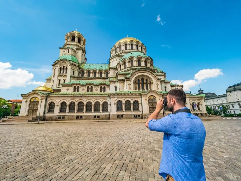 мъж, който прави снимка на катедрала в българия