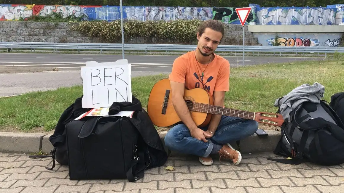 jeune musicien avec guitare en attente de faire du stop à Berlin