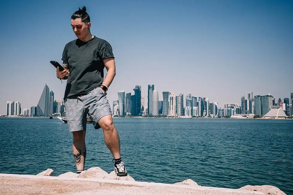Nic se tenait au bord de l'eau devant les gratte-ciel de Doha