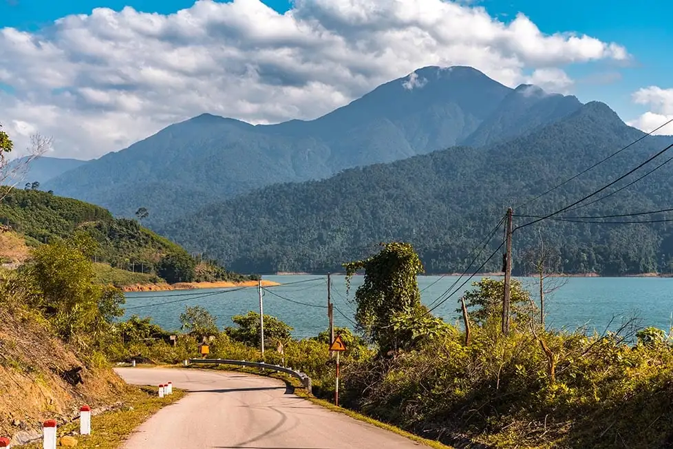 Un lac bleu avec une route qui le longe et des montagnes au loin au Vietnam