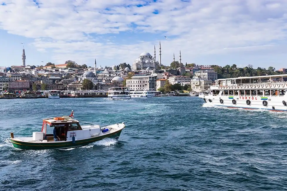 Un bateau traversant le Bosphore avec une grande mosquée et plusieurs autres minarets de mosquées plus petites au loin.