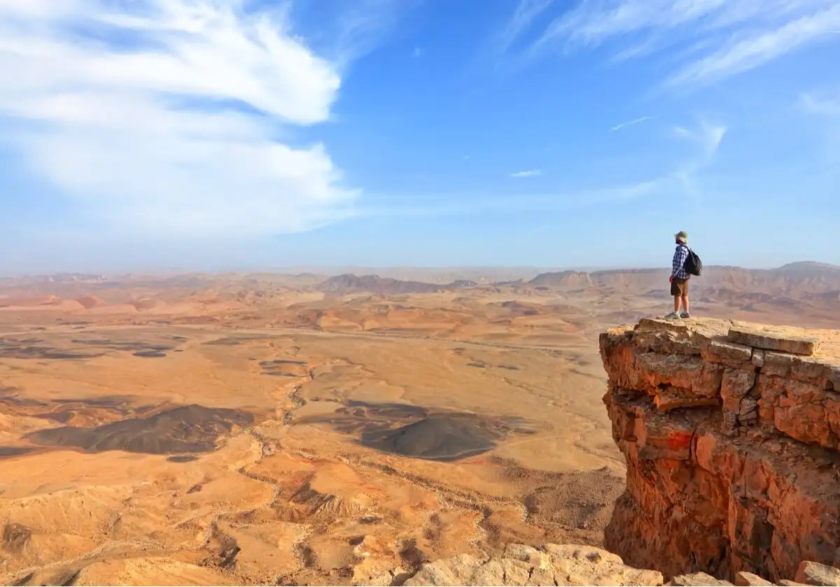 Un voyageur en Israël se tient à un point de vue surplombant la zone désertique du sud