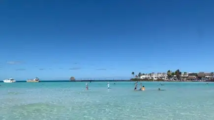 Langit biru, air jernih. Orang-orang bermain di laut. Playa Norte Pulau Mujeres