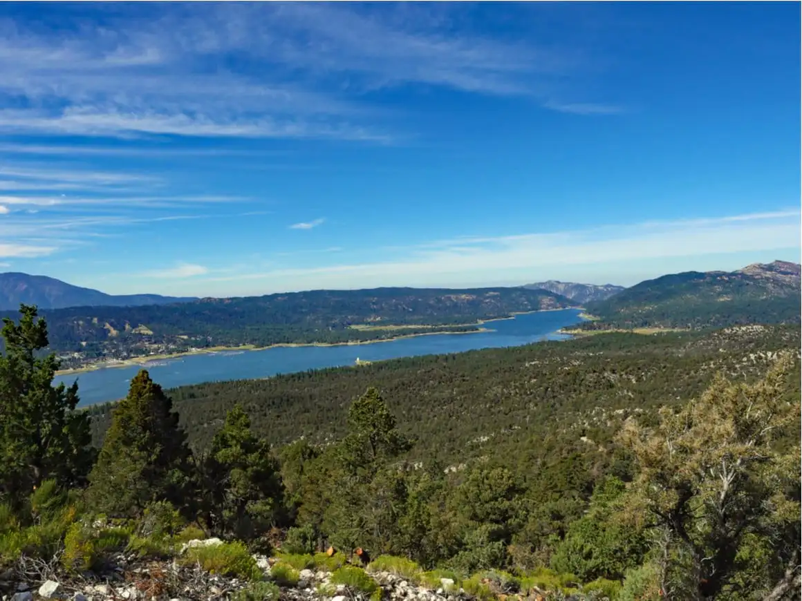 Big Bear Lake East com céu azul mostrando um resort com piscina e uma floresta de pinheiros em vista aérea