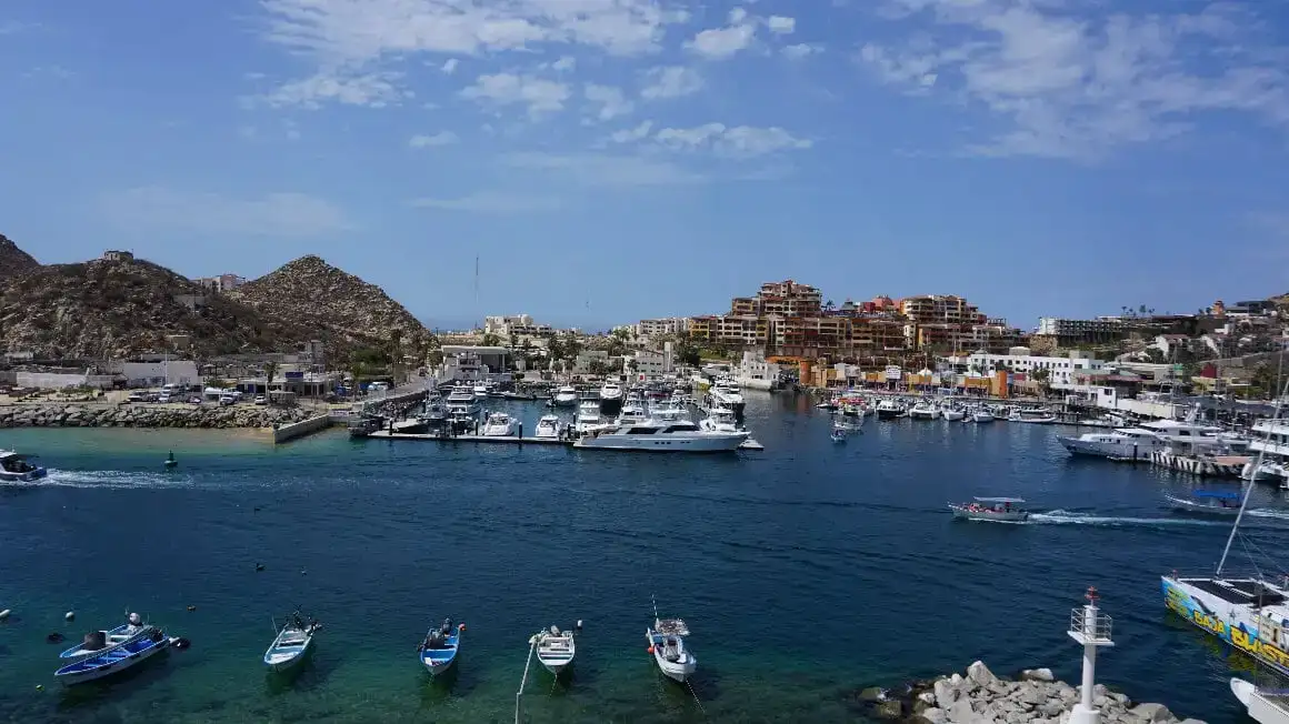 Perairan biru kehijauan sebening kristal di pantai Santa Maria Cabo San Lucas, dengan perahu dan formasi batuan.